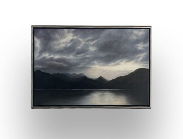 A framed painting depicts a dark, cloudy sky over distant mountains with their reflection visible on a calm lake.