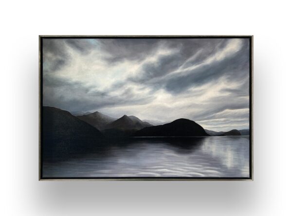A framed painting of a calm lake with dark mountains in the background under a cloudy, dramatic sky.